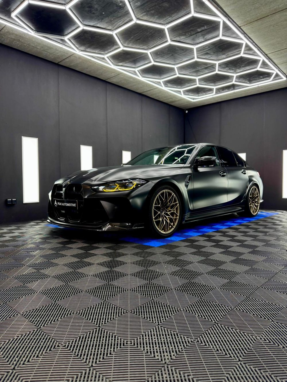 BMW M3 Competition in mat zwart met gouden velgen in de werkplaats